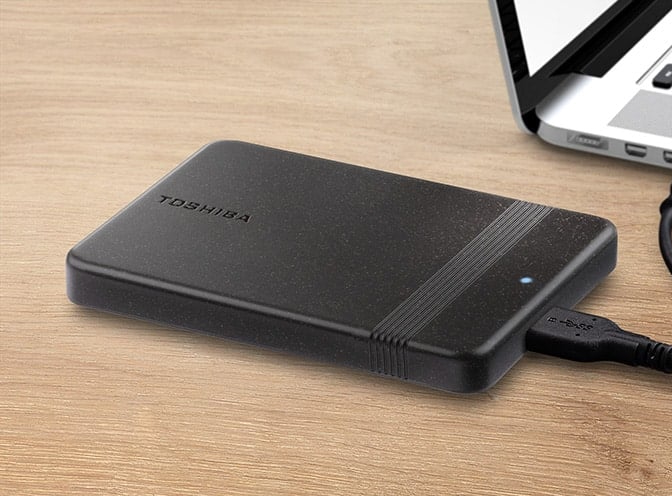 A Toshiba Canvio Ready hordozható merevlemez fekete színű, lekerekített sarkú házzal és egy keskeny, fogáshoz szolgáló sávval rendelkezik.