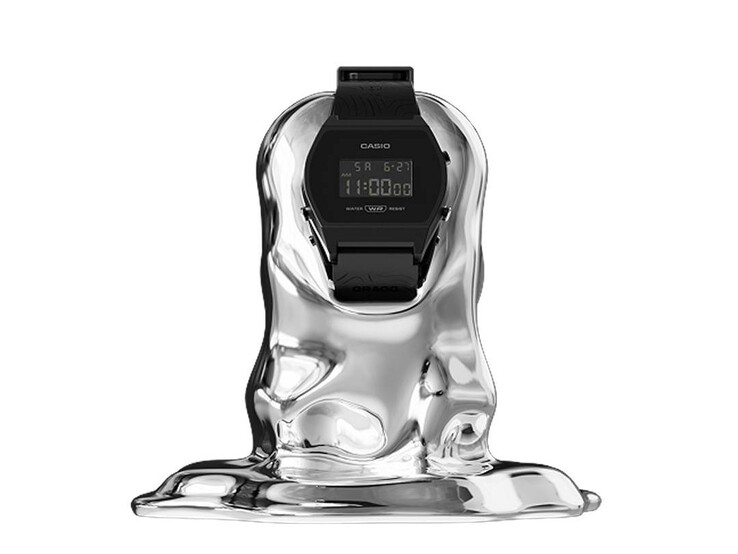 Casio x GRAGG LW-204GRAGG-1BDF digitális karóra, amely egy szoborszerű ezüst állványon helyezkedik el fehér háttér előtt.