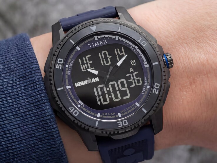 Fekete Timex Ironman Adrenaline ana-digi karóra sötétkék szíjjal és kék koronával, csuklón ábrázolva.