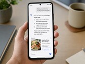 Egy okostelefont tartó kéz, amelyen egy mesterséges intelligencia által generált válasz látható, alatta egy szponzorált hirdetéssel
