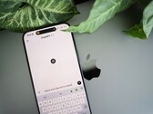 Okostelefon, amelyen a ChatGPT alkalmazás fut, egy laptopon fekszik, növényi levelek mellett