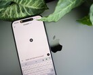 Okostelefon, amelyen a ChatGPT alkalmazás fut, egy laptopon fekszik, növényi levelek mellett