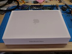 A MacBook Neo kiskereskedelmi doboza egy munkapadon az SSD frissítéshez szükséges szétszerelés előtt