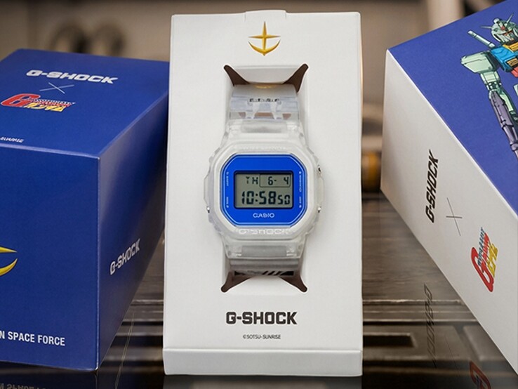 Casio G-Shock x Mobile Suit Gundam DW-5600 átlátszó tokkal és szíjjal, kék lünettával, E.F.S.F. márkajelzéssel és Gundam-művekkel díszített gyűjtői csomagolással.