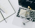Miniatűr bevásárlókosár egy laptop billentyűzetén, a képernyőn a „Vásárolj most” felirattal