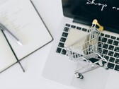 Miniatűr bevásárlókosár egy laptop billentyűzetén, a képernyőn a „Vásárolj most” felirattal