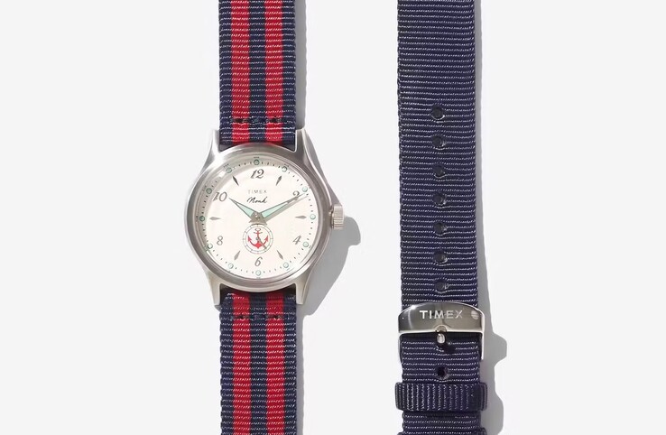 A Noah x Timex MK1 Anchor piros-fekete szövet szíjjal, mellette egy egyszínű kék szíjjal.