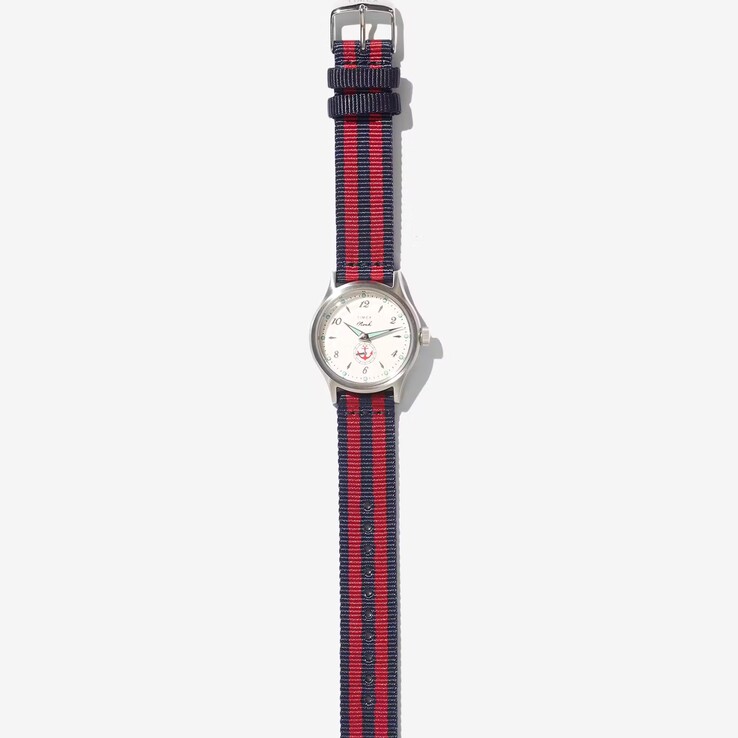 Noah x Timex MK1 Anchor karóra ezüst színű, 36 mm-es tokban, krém színű számlappal, horgonyos grafikával, valamint sötétkék és piros csíkos szövet szíjjal.