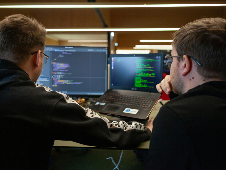 Kutatók kódot elemeznek kettős monitoron (Kép forrása: Flipsnack / Unsplash)