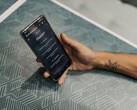 Egy kéz okostelefont tart egy mintás asztal fölött, a telefonon meg van nyitva a ChatGPT alkalmazás