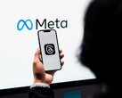 Egy kéz egy okostelefont tart egy nagy Meta-logó előtt
