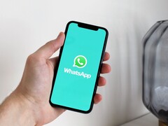 Egy kéz egy okostelefont tart, amelyen a WhatsApp alkalmazás van megnyitva