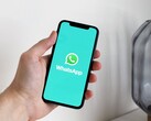 Egy kéz egy okostelefont tart, amelyen a WhatsApp alkalmazás van megnyitva