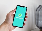 Egy kéz egy okostelefont tart, amelyen a WhatsApp alkalmazás van megnyitva