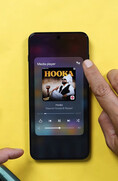 Egy OnePlus okostelefon, amelyen a médialejátszó-widget látható; a felhasználó az audio-kimeneti ikonra koppint, hogy elérje a Bluetooth-hangmegosztás vezérlőelemeit.
