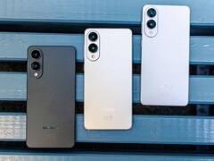 Három Samsung Galaxy Edge okostelefonok fekete, ezüst, és fehér kivitelben egymás mellé helyezett egy kék padon, bemutató az ultra-vékony hátsó kialakítás és a kettős kamera beállításHárom Samsung Galaxy Edge okostelefonok fekete, ezüst, és fehér kivitelben egymás mellé helyezett egy kék padon, bemutató az ultra-vékony hátsó kialakítás és a kettős kamera beállítás (Kép forrása: Notebookcheck)