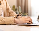 Egy világos íróasztalnál nyitott laptop billentyűzetén gépelő kezek