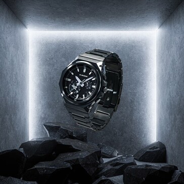 A G-Shock GST-B1000BD-1A egy betonozott kiállítótérben sötét sziklák fölé függesztve, kiemelve fekete rozsdamentes acélszerkezetét.