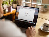 Egy személy laptop előtt, amelyen a Google kezdőlapja látható, egy csésze kávé mellett