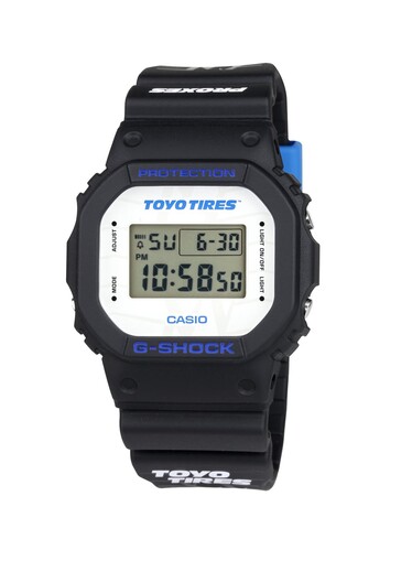 A fehér számlapon a Toyo Tires márkajelzés látható, míg a kék betűk kontrasztot adnak a klasszikus négyzet alakú G-Shock dizájnnak.