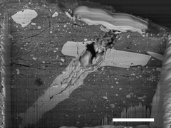 Pásztázó elektronmikroszkópos felvétel egy mikrometeorit-becsapódási kráterről a Bennu aszteroida anyagának egy részecskéjében (A kép forrása: NASA, és Zia Rahman)