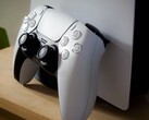 Egy PS5 konzolnak támasztott PlayStation 5 DualSense kontrollert ábrázoló kép