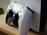 Egy PS5 konzolnak támasztott PlayStation 5 DualSense kontrollert ábrázoló kép