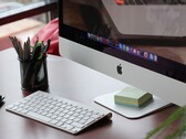 Egy asztalon álló iMac, amelynek képernyőjén látható a macOS dokkoló, előtte pedig egy Apple billentyűzet található