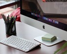 Egy asztalon álló iMac, amelynek képernyőjén látható a macOS dokkoló, előtte pedig egy Apple billentyűzet található
