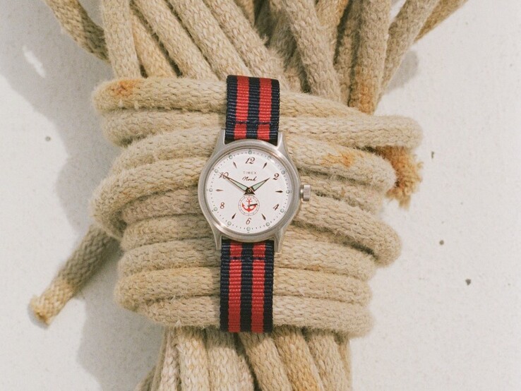 Noah x Timex MK1 Anchor karóra ezüstszínű, 36 mm-es tokban, fehér számlappal, horgonyos grafikával és sötétkék-piros csíkos szövet szíjjal.