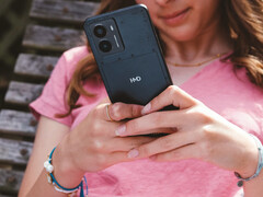 A HMD Fusion okostelefon promóciós képe, amely a telefont egy nő kezében mutatja be, a hátlapon lévő HMD logó közelképével. (Kép forrása: HMD)