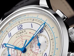 A Timex Marlin Neo Classic Chronograph krém színű számlapjának közeli képe, kék mutatókkal és arab számokkal, piros tachyméter-jelölésekkel, valamint a külső szélén körbefutó kék távmérő-skálával.