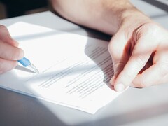 Egy kéz kék golyóstollal aláír egy dokumentumot