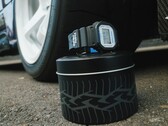 Casio G-Shock DW5600TT25-1 x Toyo Tires karóra, amely egy autógumi-témájú fémdobozon van elhelyezve egy autó kereke mellett.