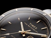 Közelkép a fekete számlapos Timex Waterbury Heritage Automatic óráról, amelyen láthatók a csiszolt, fényes mutatók, az órajelölők, a nap-dátum kijelző és a fekete keret.