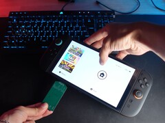 Yu a Better Gaming YouTube-csatornáról, egyik kezében egy Nintendo Switch 2, a másikban pedig egy nyílt forráskódú zöld PCB-adaptert tart, és megpróbálja behelyezni a készülék microSD Express foglalatába (Kép forrása: Better Gaming via YouTube)