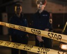 Két rendőr áll éjszaka egy Stop feliratú sárga szalag mögött