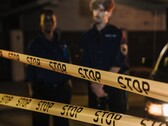 Két rendőr áll éjszaka egy Stop feliratú sárga szalag mögött