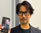 Hideo Kojima a Physint poszterét mutatja a telefonján