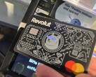 A világító szemekkel ellátott Revolut-kártyát használjuk az érintésmentes terminálon történő fizetéshez
