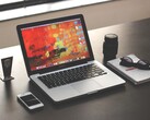MacBook Pro egy sötét íróasztalon, okostelefon, szemüveg és jegyzetfüzet mellett