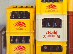 Asahi sörösüvegekkel töltött, egymásra helyezett sárga és fehér műanyag ládák, japán szöveggel és piros logókkal. (Kép forrása: Alazne Lazcano fotója a Pexels-en keresztül)