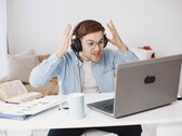 Fejhallgatót viselő férfi frusztráltan emeli fel a kezét egy laptop előtt