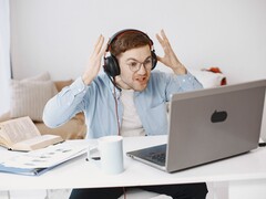 Fejhallgatót viselő férfi frusztráltan emeli fel a kezét egy laptop előtt
