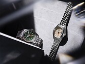 A zöld számlapos Seiko 5 Sports Field GMT HDB001 és a krém színű számlapos HDB002 modellek egymás mellett láthatók rozsdamentes acélból készült, ötszemcsés karkötőn, mindkettő rögzített 24 órás kerettel és narancssárga GMT-mutatóval rendelkezik.