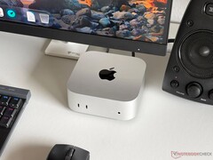 Apple M6 Mac mini egy íróasztalon, játékkonfigurációban, monitorral, billentyűzettel, egérrel és hangszóróval.