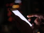 A sötétben egy okostelefont tartó kéz, amelynek képernyője világít