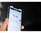 Egy fénykép, amelyen egy okostelefont tartó kéz látható, a képernyőn pedig a Google Search kezdőlapja van megnyitva. (A kép forrása: Solen Feyissa a Flickr-en)