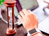Homokóra egy laptop billentyűzetén ülő kéz mellett