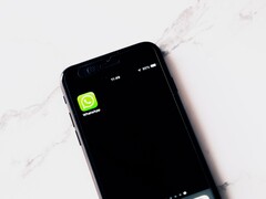 Fehér asztalon fekvő okostelefon, amelyen a WhatsApp alkalmazás látható